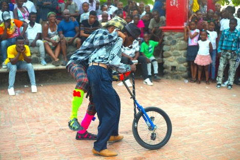 Comedian Antoine Saint-Jacques Jean, also known as Pè Antoine (Father Antoine), attempts to climb on top of the shoulders of Micken ‘Poet Funeste’ Jeanite to mimic the stunt. Photo by Onz Chéry/ The Haitian Times 